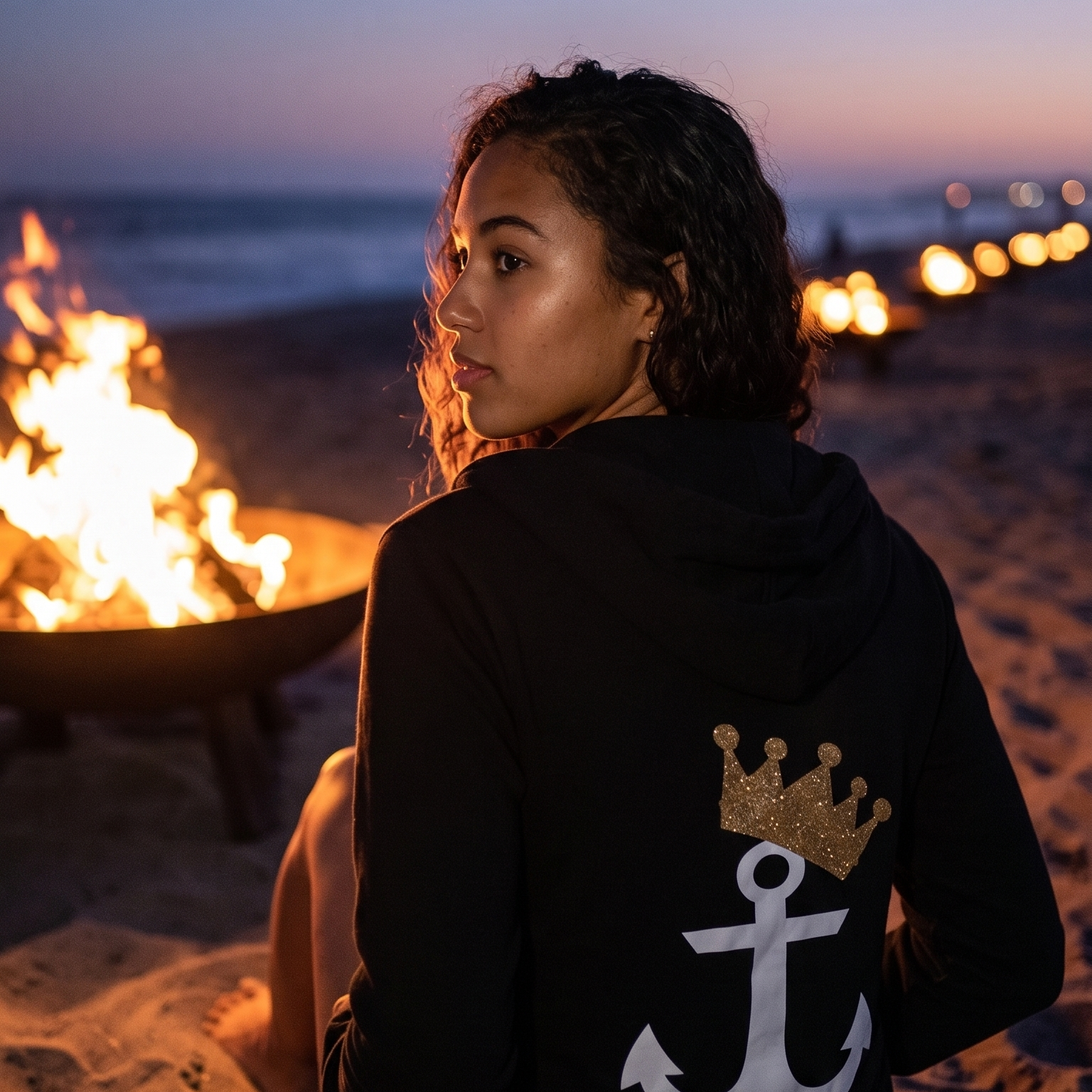 Model wearing Anchor and Crown Long Sleeve Hoodie at beach bonfire (Square)